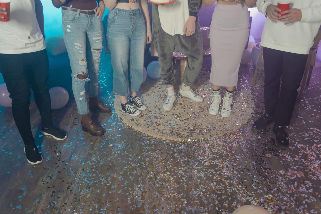 A group of friends celebrating indoors with confetti and balloons, creating a festive atmosphere.